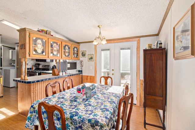 dining space featuring french doors, a textured ceiling, and light hardwood / wood-style floors