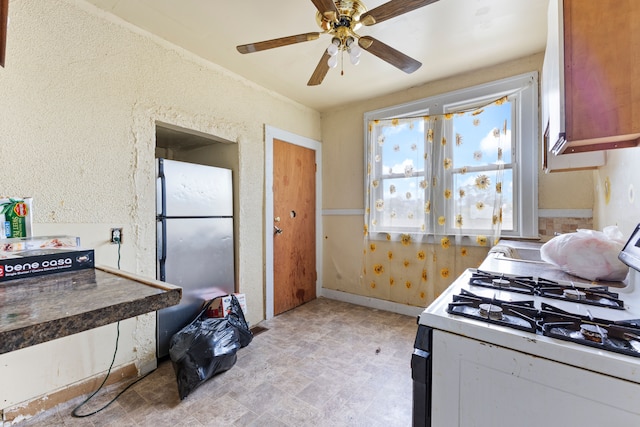 kitchen with stainless steel fridge, white gas range, and ceiling fan