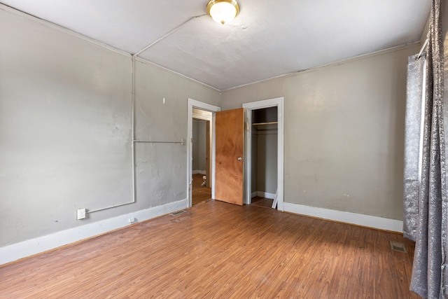 unfurnished bedroom featuring hardwood / wood-style flooring, a closet, and crown molding