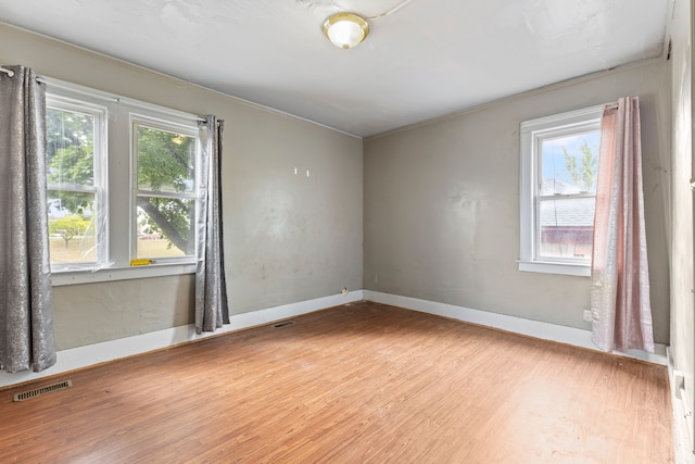 unfurnished room featuring plenty of natural light, light hardwood / wood-style floors, and ornamental molding