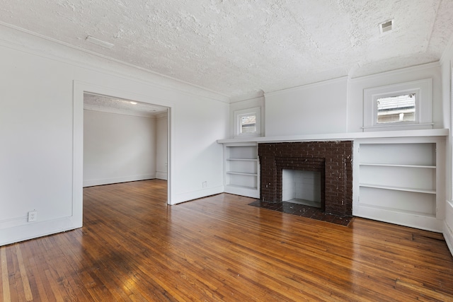 unfurnished living room with a fireplace, dark hardwood / wood-style flooring, a textured ceiling, and ornamental molding