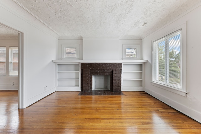 unfurnished living room with a fireplace, a textured ceiling, and hardwood / wood-style flooring