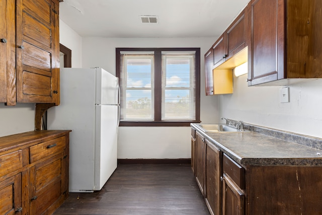 kitchen featuring white fridge, dark wood-type flooring, and sink