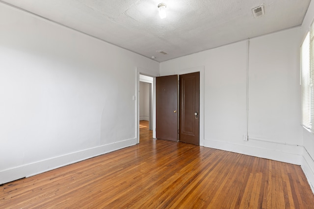 unfurnished room with hardwood / wood-style floors and a textured ceiling