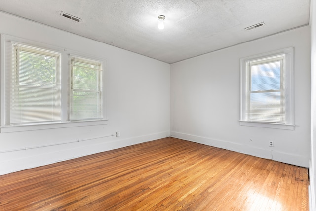 spare room featuring hardwood / wood-style floors and a textured ceiling