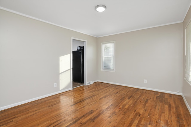 empty room with wood-type flooring and ornamental molding