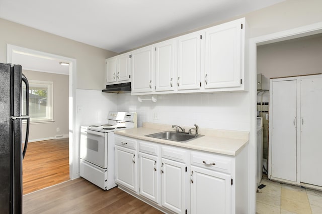 kitchen featuring black refrigerator, white cabinetry, white range with electric stovetop, and sink