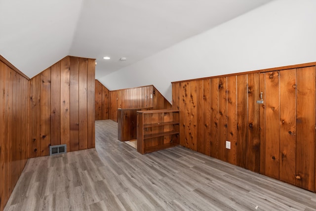 bonus room featuring lofted ceiling, wood walls, and light wood-type flooring