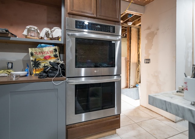 kitchen featuring light tile patterned floors and stainless steel double oven