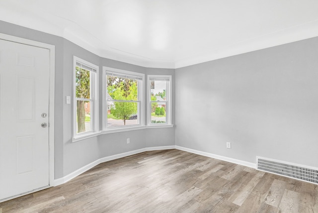 empty room featuring crown molding and light wood-type flooring