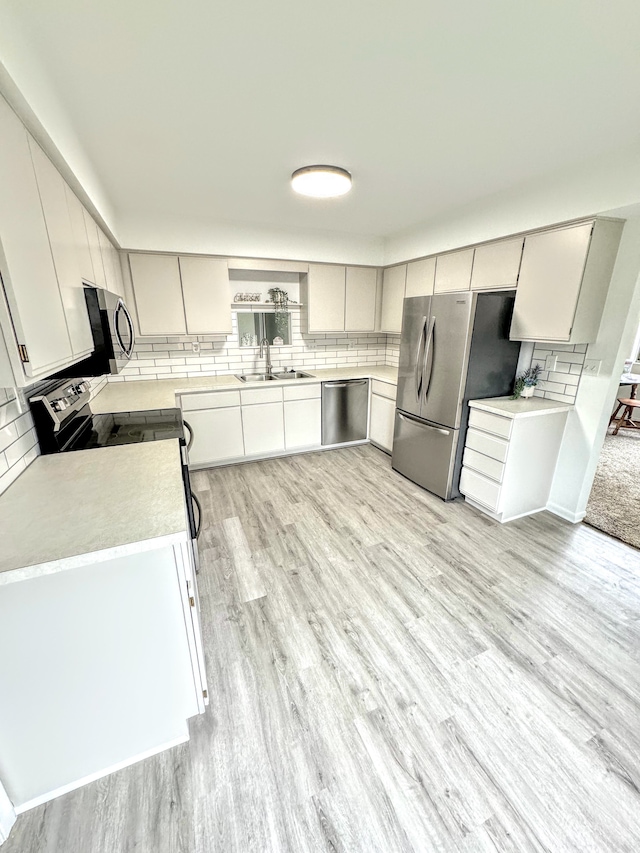 kitchen featuring backsplash, light hardwood / wood-style flooring, white cabinets, and stainless steel appliances