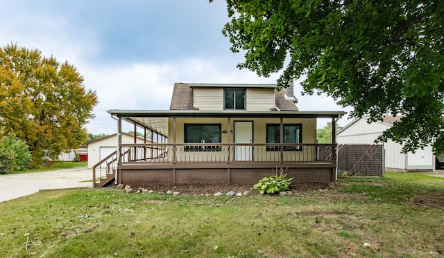 farmhouse-style home with covered porch, a garage, a front lawn, and an outdoor structure