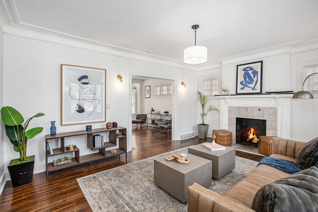 living room featuring a fireplace, crown molding, and dark wood-type flooring