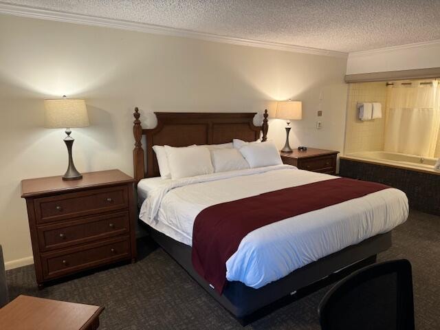 bedroom featuring dark colored carpet, ornamental molding, and a textured ceiling