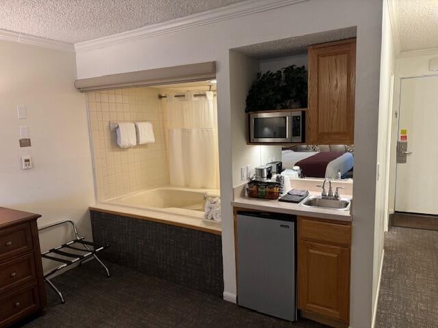 kitchen featuring sink, ornamental molding, a textured ceiling, and appliances with stainless steel finishes