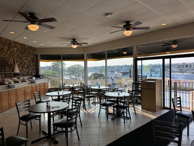 dining space featuring light tile patterned floors, a water view, and ceiling fan