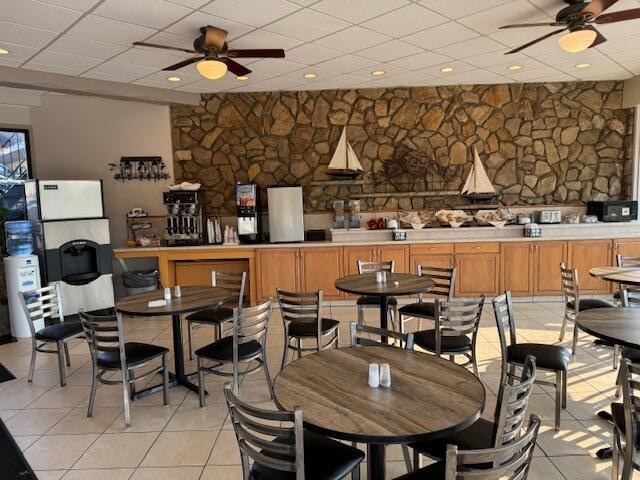 tiled dining room featuring ceiling fan and a drop ceiling