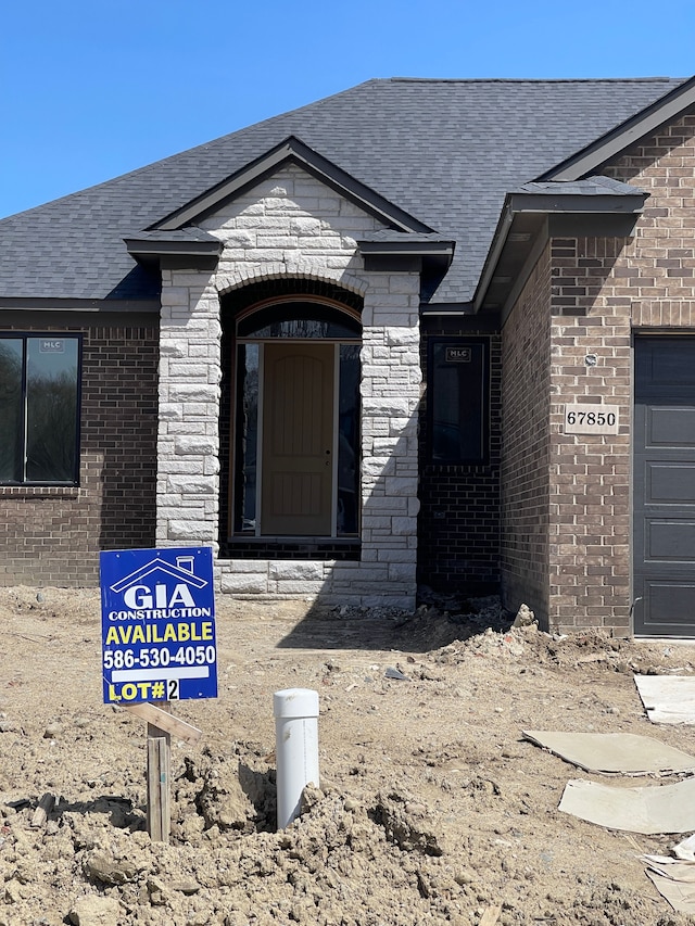 view of exterior entry featuring brick siding and roof with shingles
