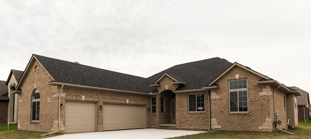 single story home featuring a front yard, driveway, a shingled roof, a garage, and brick siding