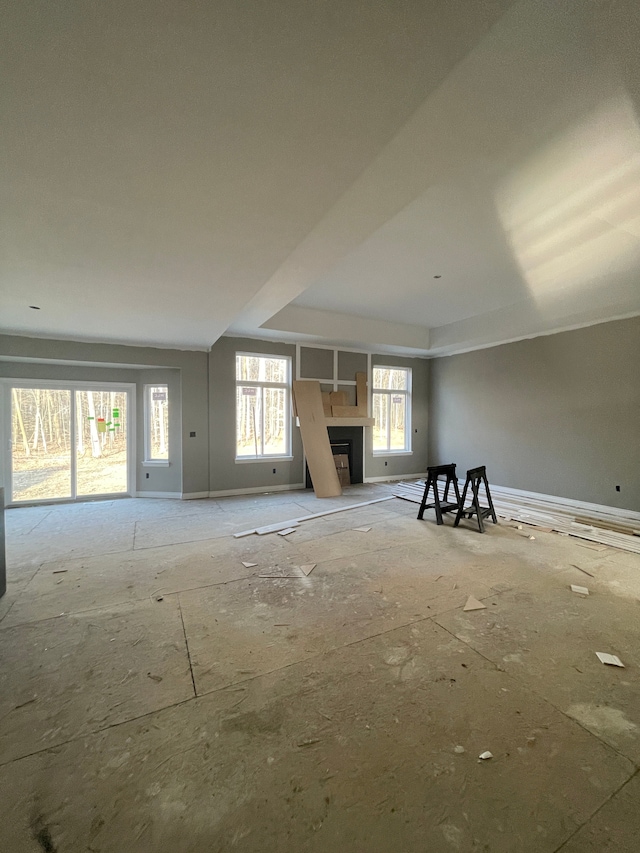 interior space featuring a tray ceiling, baseboards, and a fireplace