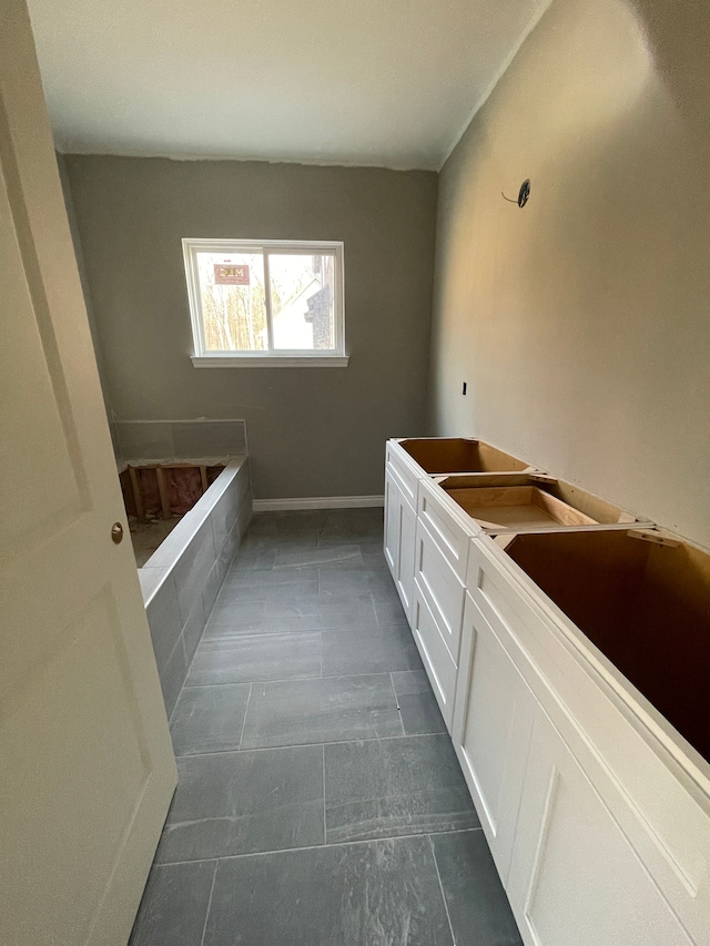 bathroom with baseboards and a bath