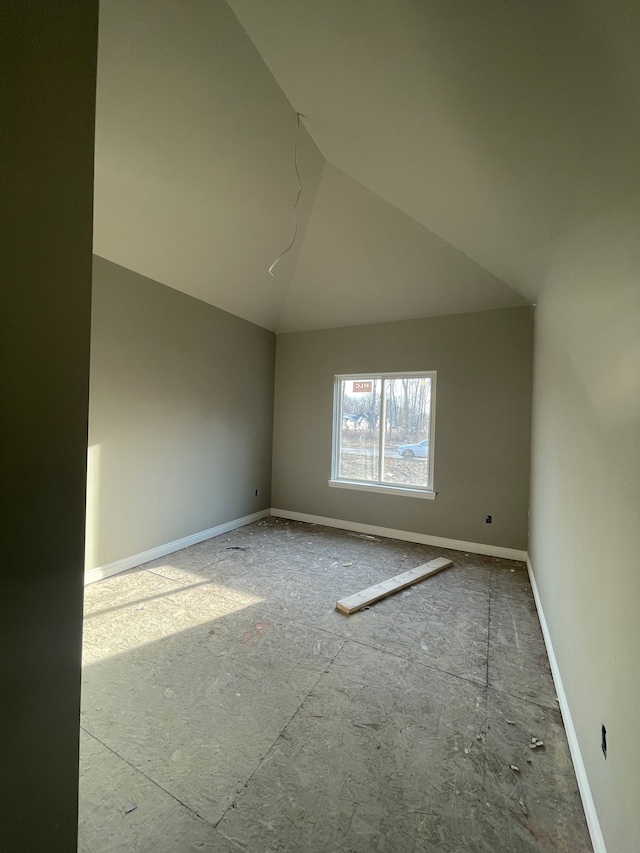 empty room featuring baseboards and vaulted ceiling