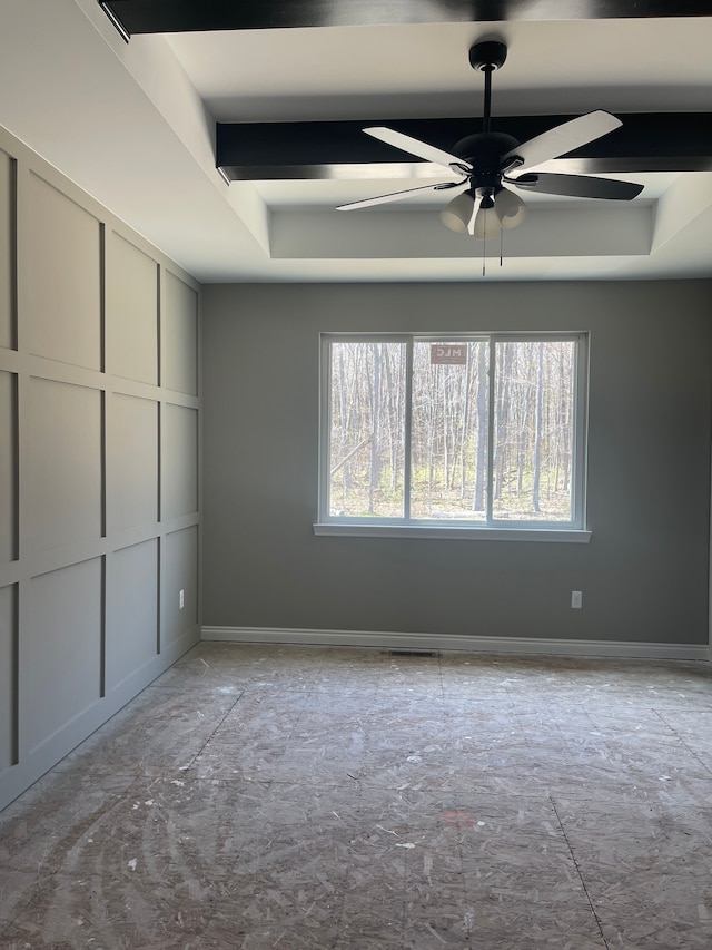 unfurnished room with a raised ceiling, ceiling fan, and baseboards