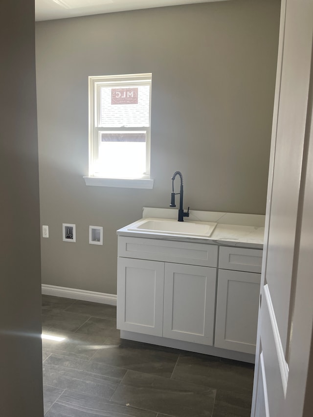 clothes washing area featuring a sink, baseboards, laundry area, and hookup for a washing machine