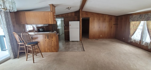 kitchen with light carpet, lofted ceiling with beams, white fridge, a kitchen bar, and kitchen peninsula