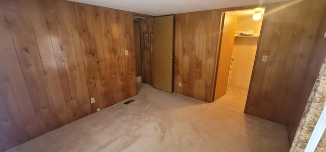 unfurnished room with wood walls and light colored carpet