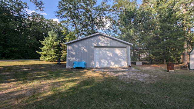 exterior space featuring a lawn, a garage, and an outbuilding