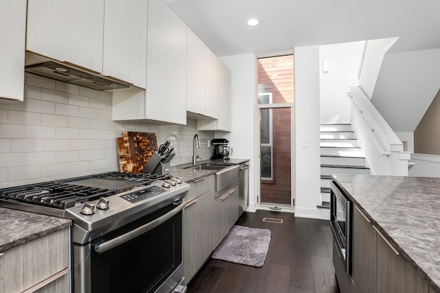 kitchen with appliances with stainless steel finishes, tasteful backsplash, dark wood-type flooring, exhaust hood, and white cabinetry