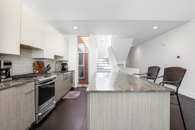 kitchen with a center island, dark wood-type flooring, backsplash, a kitchen breakfast bar, and gas stove