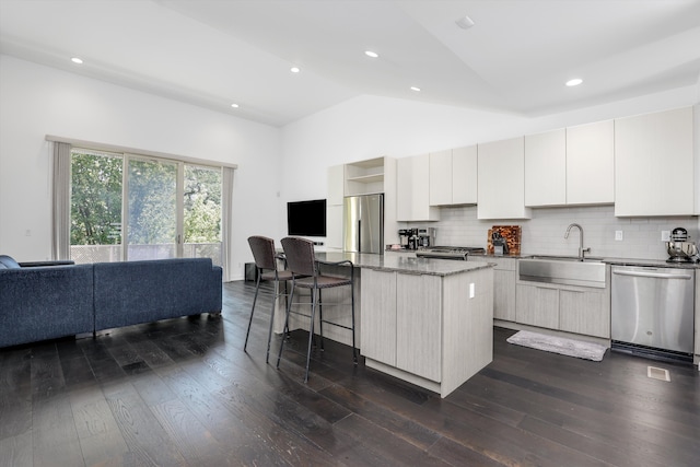 kitchen featuring sink, dark wood-type flooring, stainless steel appliances, lofted ceiling, and a kitchen island