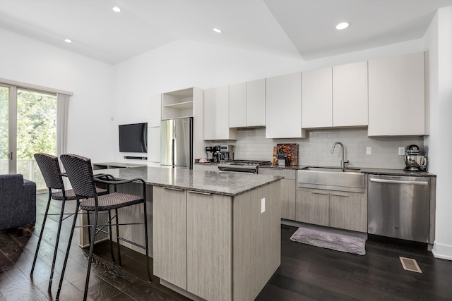 kitchen featuring a center island, lofted ceiling, sink, appliances with stainless steel finishes, and dark hardwood / wood-style flooring