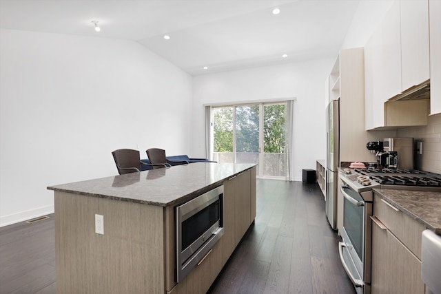 kitchen with tasteful backsplash, stainless steel appliances, vaulted ceiling, a center island, and dark hardwood / wood-style floors