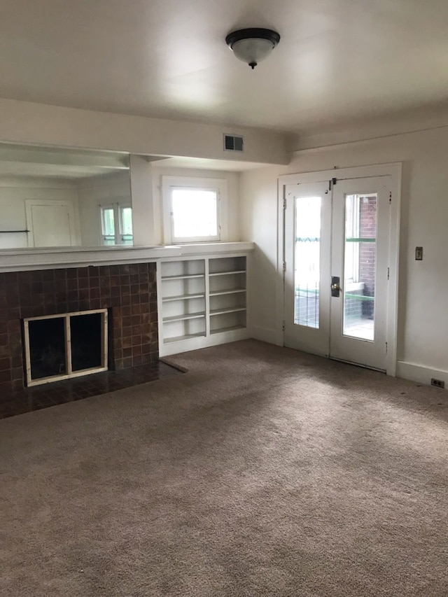 unfurnished living room featuring carpet floors, a fireplace, and french doors