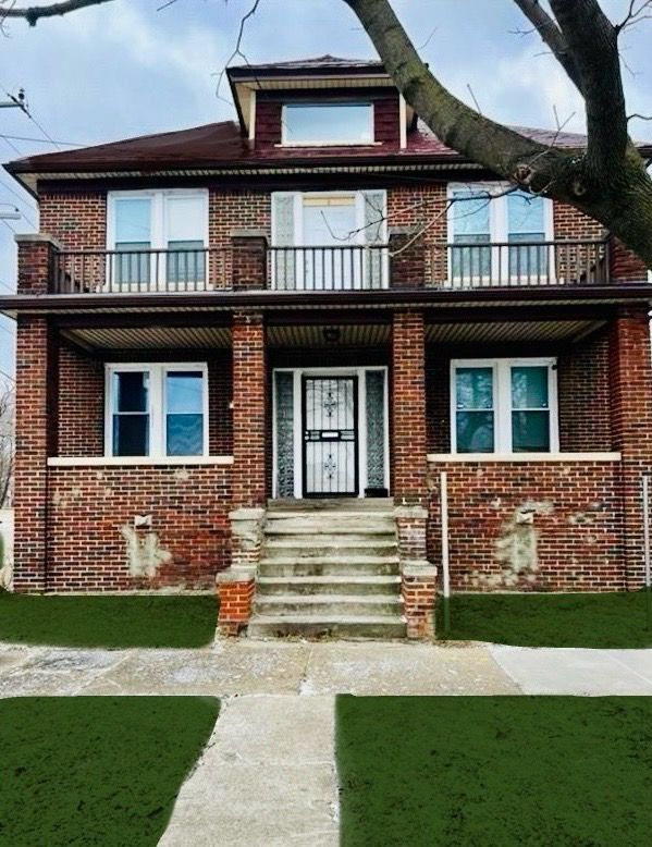 back of house with a balcony and brick siding