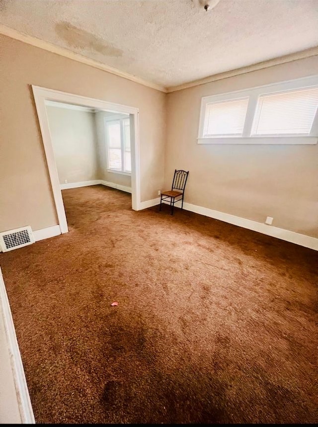 carpeted empty room with a textured ceiling and crown molding