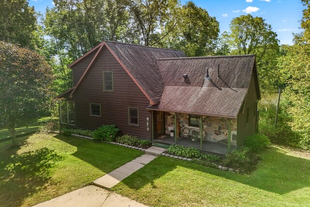 2488 Wilson St, Hillsdale, MI 49242 - view of front of house with covered porch, a front lawn, stone siding, and a shingled roof