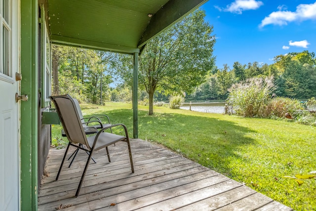 wooden terrace with a water view and a yard