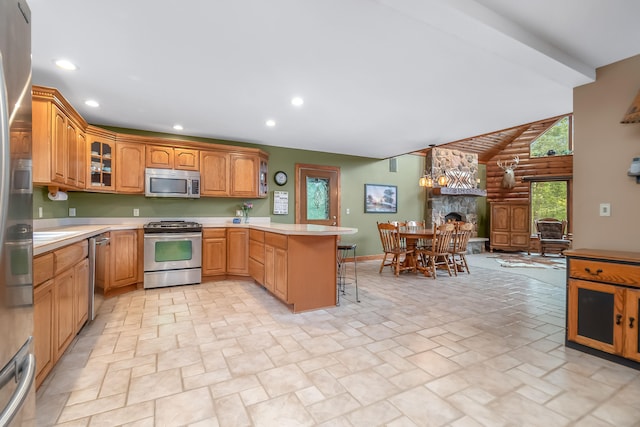 kitchen featuring hanging light fixtures, a breakfast bar area, a fireplace, kitchen peninsula, and stainless steel appliances