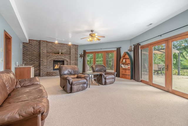 living room with carpet flooring, a brick fireplace, a wealth of natural light, and ceiling fan