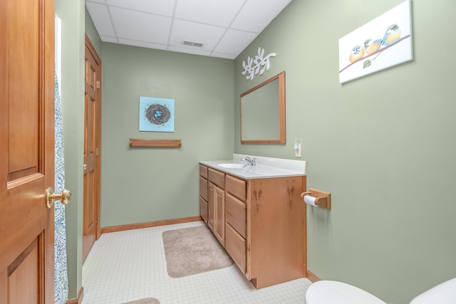 bathroom featuring a drop ceiling, vanity, and toilet