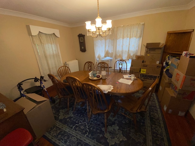 dining area with hardwood / wood-style flooring, ornamental molding, and an inviting chandelier