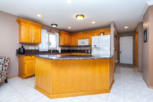 kitchen featuring a center island, dark stone countertops, white appliances, and light tile patterned floors