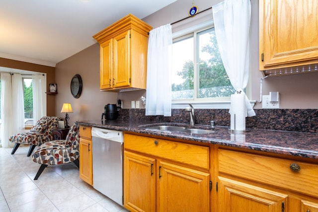 kitchen with dishwasher, sink, dark stone countertops, light tile patterned flooring, and ornamental molding