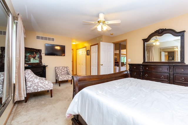 bedroom with ceiling fan, light carpet, and multiple closets