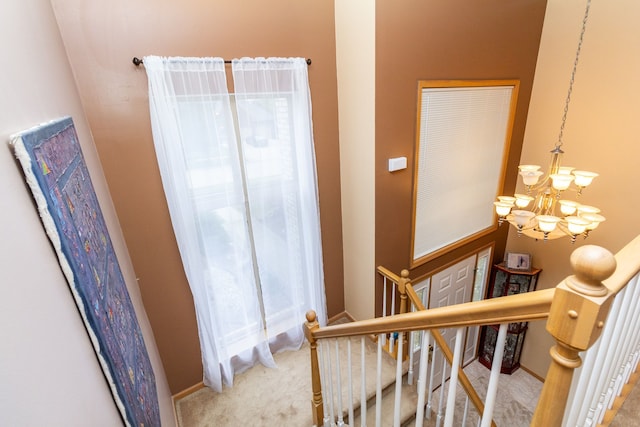 staircase featuring carpet flooring and a chandelier