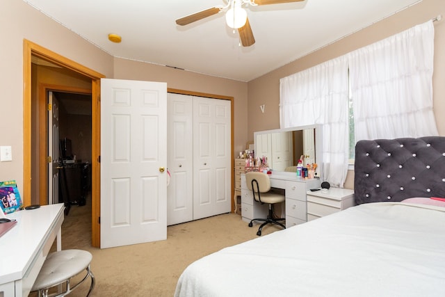 bedroom with ceiling fan, light colored carpet, and a closet